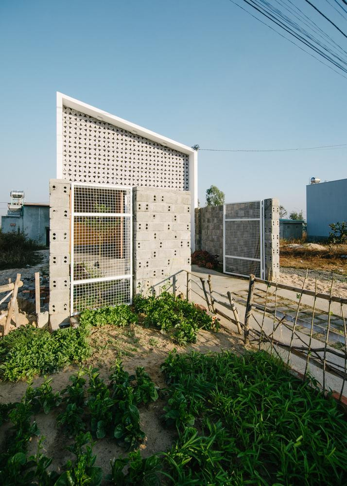 Do đó, họ đã nhờ các kiến trúc sư thiết kế ngôi nhà ống một tầng mái lệch trên diện tích đất 5 x 23 mét. Để khắc phục việc ngôi nhà quay về hướng Tây, đội thiết kế đã làm mặt tiền 2 lớp để giảm sức nóng của ánh nắng mặt trời gồm một bức tường bằng gạch hoa văn thông gió, phía trong có nhiều cửa kính nhỏ. Bức tường này còn có tác dụng trang trí nội thất cho ngôi nhà, nhờ việc ánh sáng xuyên qua các khối gạch hoa văn tạo nên không gian ánh sáng đa chiều ở phòng khách. Vách kính phía sau có thể đóng mở dễ dàng để điều chỉnh lượng gió vào nhà theo mùa. Các khối chức năng trải dài theo chiều dọc ngôi nhà. Từ cửa vào là phòng khách, ghế sofa tối màu được kê sát tường để lấy không gian đi lại, ngay dưới phòng khách là giếng trời chiếu xuống một khoảng đất nhỏ trồng cây xanh. Phòng khách được ngăn cách với bếp bằng một tấm gỗ trang trí. Sau bếp là không gian phòng ngủ của cặp vợ chồng trẻ và em bé mới sinh, phòng ngủ có cửa sổ kính lớn để nhìn ra khu vườn phía sau, liền kề với nhà vệ sinh. Khu vườn phía sau nằm dưới giếng trời lớn, là nơi cung cấp ánh sáng tự nhiên cho cả ngôi nhà cũng như được gia chủ tận dụng làm nơi phơi đồ mà không lo mưa, gió. Ngôi nhà sử dụng màu trắng làm chủ đạo, trong khi đồ nội thất và sàn bê tông có màu xám giúp tôn lên màu sắc của các vật liệu gỗ và màu xanh tươi của cây cỏ trong nhà. Nhờ hệ thống giếng trời, từ mọi nơi trong nhà đều có thể nhìn thấy ánh sáng tự nhiên và màu xanh của thiên nhiên. Tất cả mọi thứ trong ngôi nhà đều hết sức đơn giản và nhẹ nhàng, nhưng khi kết hợp lại đã tạo ra không gian lí tưởng cho một gia đình trẻ.