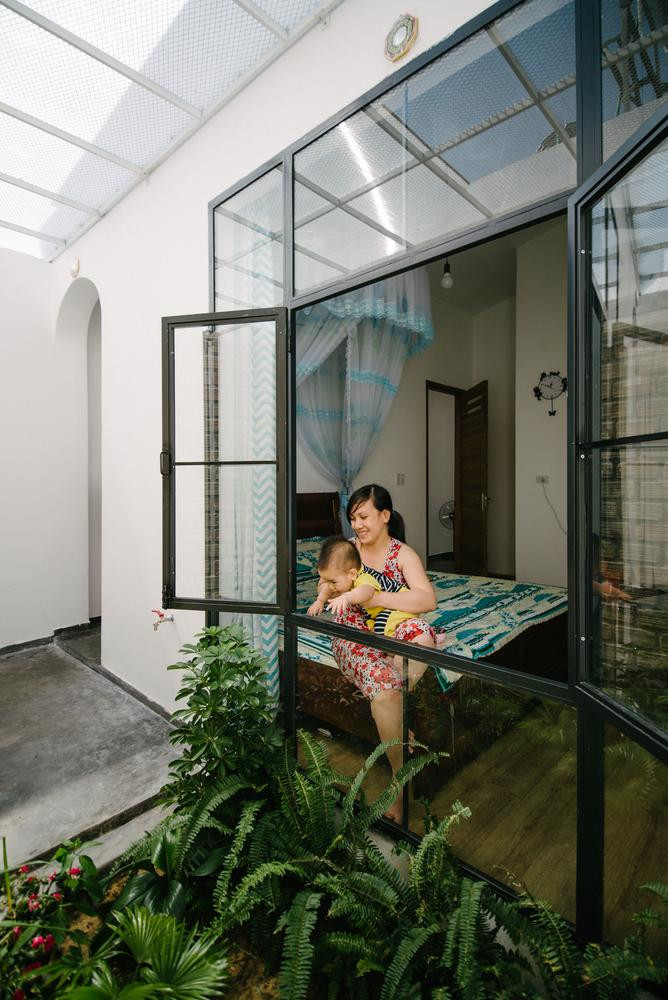 Sau bếp là không gian phòng ngủ của cặp vợ chồng trẻ và em bé mới sinh, phòng ngủ có cửa sổ kính lớn để nhìn ra khu vườn phía sau, liền kề với nhà vệ sinh.