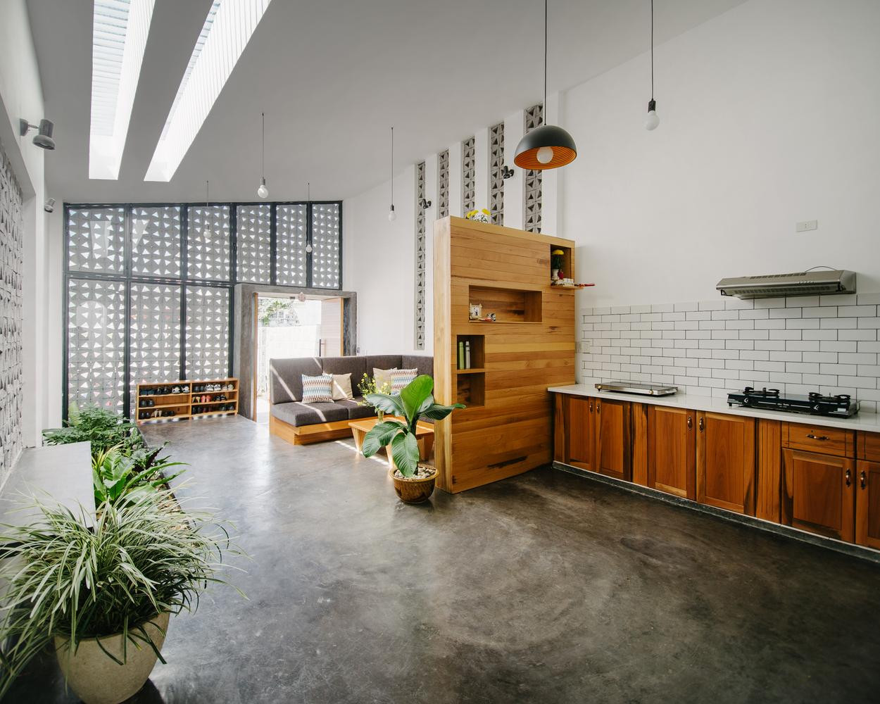 Các khối chức năng trải dài theo chiều dọc ngôi nhà. Từ cửa vào là phòng khách, ghế sofa tối màu được kê sát tường để lấy không gian đi lại, ngay dưới phòng khách là giếng trời chiếu xuống một khoảng đất nhỏ trồng cây xanh.