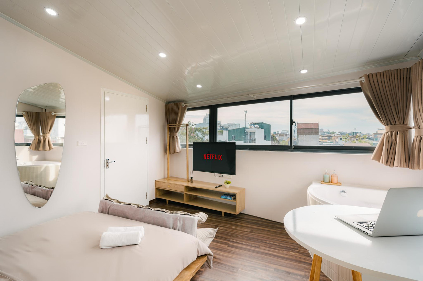 Gia chủ bố trí hệ tivi thông minh với tay nâng và xoay đa chiều để ngồi ở sofa bệt hoặc nằm trên giường đều xem được mà vẫn nhìn ra phố cổ.