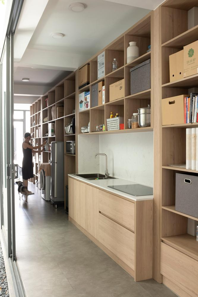 Trong nhà, không có ranh giới cụ thể giữa các không gian vì phòng bếp chính là phòng ăn, phòng ngủ cũng là nơi làm việc. Việc sử dụng kết hợp không gian được thể hiện dọc theo hành lang chính, nơi có một kệ tủ lớn và dài 14 mét gắn vào tường. Chiếc kệ này kéo dài, được sử dụng cho nhiều mục đích, là nơi để các vật dụng gia đình như nhà bếp, tủ đựng thức ăn, thiết bị, tủ lạnh, máy giặt, kệ giày dép, kệ sách,…Mọi thứ được sắp xếp và lấp đầy trong một cấu trúc có trật tự tạo nên sự đa dạng và linh hoạt. Không giống như nhà phố điển hình ở TP Hồ Chí Minh, ngôi nhà không mở ra bên ngoài mà hướng vào bên trong, Hai mặt tiền đơn giản hết sức có thể vì cả mặt trước và mặt sau chỉ có một khoảng hở “vừa đủ” đón ánh sáng ban ngày và thông gió, tránh ồn và ô nhiễm không khí cũng như duy trì sự riêng tư và thân mật của gia chủ. Ngôi nhà dành cho người hướng nội nên được thiết kế để nhìn từ trong ra ngoài và nhận được năng lượng từ sự phản chiếu bên trong. Các cửa trượt đều làm bằng kính để tăng sự rộng rãi cho không gian cũng như ánh sáng cho cả ngôi nhà. Cầu thang và nhà vệ sinh được bố trí ở phía trước nhà, sân trong nằm ở trung tâm của ngôi nhà. Còn bếp, phòng khách và các phòng ngủ được bố trí phía sau ở hai bên sân trong, tạo sự thông thoáng và đón nhận ánh sáng cho cả ngôi nhà.