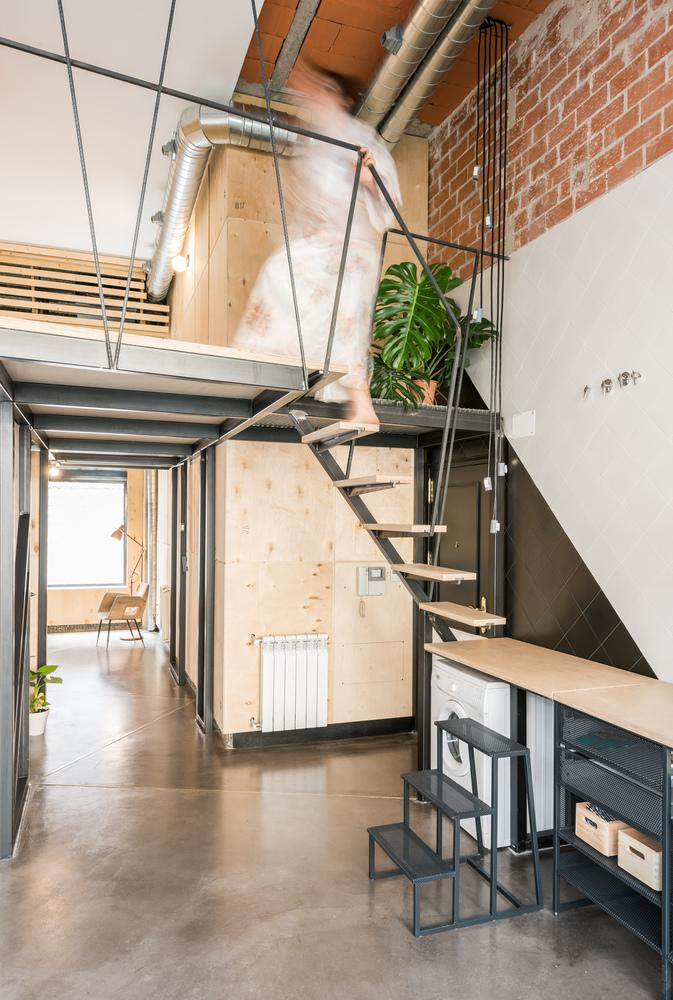 Các khung thép được đặt song song với các bức tường và bao quanh nhà vệ sinh ở giữa. Do đó, tầng lửng nằm ở phía trên đầu khu vực trung tâm của căn hộ. Phần cầu thang lên xuống tầng lửng kết hợp với tủ bếp thành nơi để đồ vô cùng tiện dụng và tiết kiệm không gian. Tầng lửng được chia làm hai bên với hai cầu thang riêng dẫn lên. Phần lửng lớn hơn nằm ở phía đông còn phần lửng nhỏ hơn nằm ở phía tây. Trên tầng lửng, mái vòm, các bức tường và cửa ra vào được bao phủ bằng ván ép tái chế (từ các thùng chứa thiết bị điện tử cũ). Để tối đa hóa ánh sáng tự nhiên trong tầng lửng, một vòm gỗ có mặt bằng gương được xây dựng để phản chiếu ánh sáng tự nhiên trong nhà lên khu vực lửng cũng như tạo hiệu ứng hình ảnh độc đáo cho căn hộ. Khu vực chung của căn hộ, bao gồm nhà bếp thông ra một sân nhỏ ở hướng Đông giúp đón ánh sáng ban mai. Tại bếp, toàn bộ phần tường và mái được làm bằng kính trong để căn hộ đón được nhiều ánh sáng nhất. Đồng thời, kết hợp với các bức tường trắng, ánh sáng từ sân hất vào sẽ được phản chiếu vào trong nhà bếp, phòng khách và không gian giải trí. Nhà vệ sinh nằm bên dưới tầng lửng được thiết kế nhỏ gọn, kết hợp tấm chắn màu xanh với gạch lát trắng cùng màu gỗ tự nhiên tạo nên phong cách cổ điển thú vị.