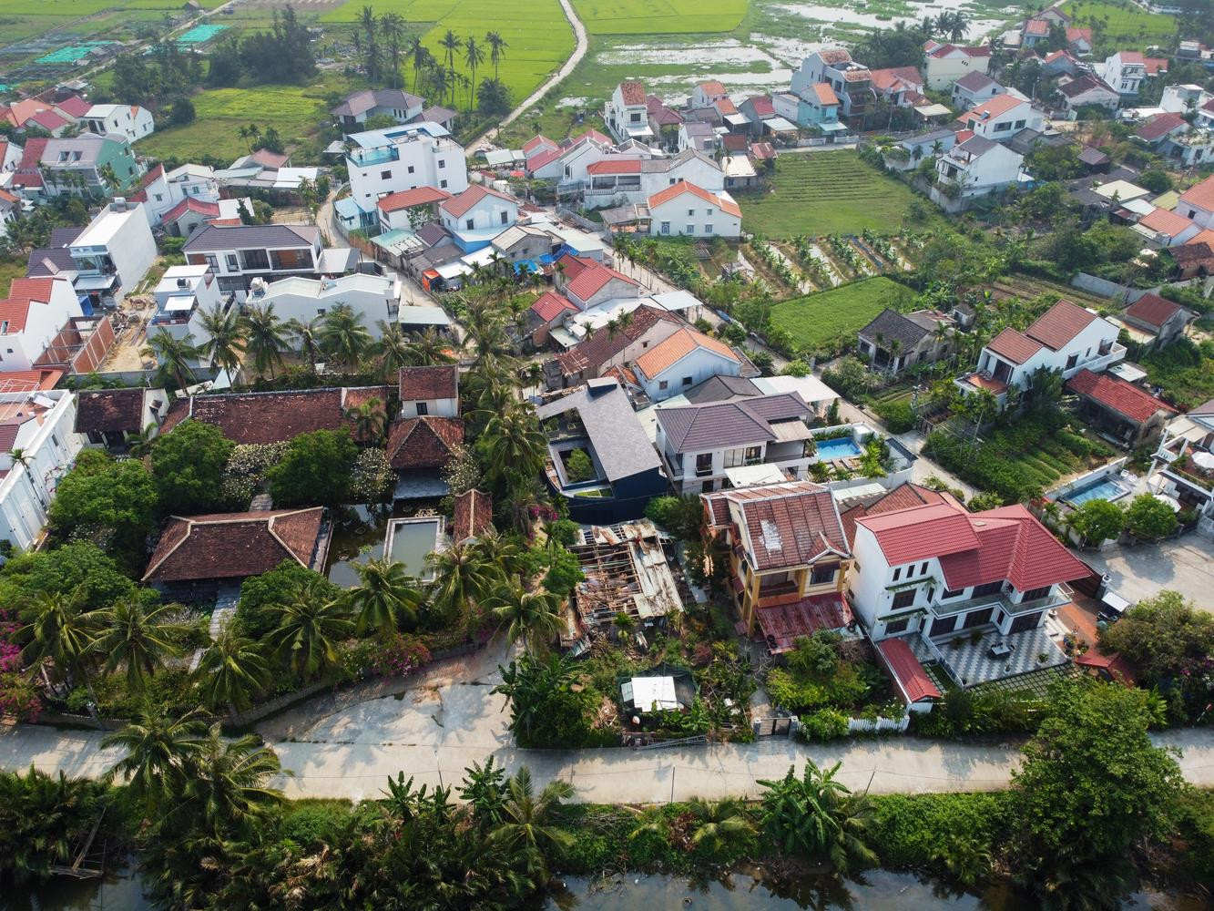 Căn nhà này tọa lạc ở ngôi làng nhỏ bên bờ sông, được bao bọc bởi cảnh quan nông nghiệp đặc trưng gần phố cổ Hội An (Quảng Nam). Gia chủ là chị Giang, một chuyên gia về môi trường từ Sài Gòn về và quan niệm không gian ngôi nhà cần được xen lẫn với cảnh quan cây xanh của địa phương, là nơi có đủ yên tĩnh để hai cậu con trai học tập. Ngôi nhà này không chỉ là tổ ấm của bốn người mà còn là nơi trú ngụ của những con chim, con nhện, hay côn trùng trong những tán lá. Ngoài ra đây còn là một trung tâm cộng đồng nhỏ, nơi chủ nhà làm việc với nhóm hoạt động vì môi trường của mình và gặp gỡ những người hàng xóm để xây dựng mối quan hệ cộng đồng. Do đó các kiến trúc sư đã thiết kế ngôi nhà rộng 180m2 theo phong cách quán xá truyền thống ở phố cổ Hội An nhưng cuộn lại như vỏ ốc bằng những vật liệu địa phương nên chi phí rất phải chăng. Ngôi nhà có kết cấu là nhà thép tiền chế 2 tầng. Tầng trệt được nâng lên cao hơn so với khu vườn ở giữa nhà để tránh ngập úng vào mùa mưa. Tại tầng trệt có các phòng chức năng như phòng khách;cạnh phòng khách là phòng bếp và phòng ăn. Các cửa trong nhà đều bằng kính có thể đóng ra mở vào giúp ngôi nhà luôn thông thoáng và tràn ngập ánh sáng tự nhiên. Ở giữa nhà là khu vườn với nhiều cây xanh cung cấp oxy và sinh khí cho người ở. Bên cạnh đồ nội thất bằng gỗ, mây, tre, gia chủ còn ưu tiên sử dụng thảm thổ cẩm kết hợp với màu xanh xám của các bức tường tạo nên một không gian mang đậm phong cách vintage. Ngoài cửa kính, ngôi nhà còn sử dụng rèm che bằng trúc để giảm sự chói chang của ánh sáng vào những ngày hè.