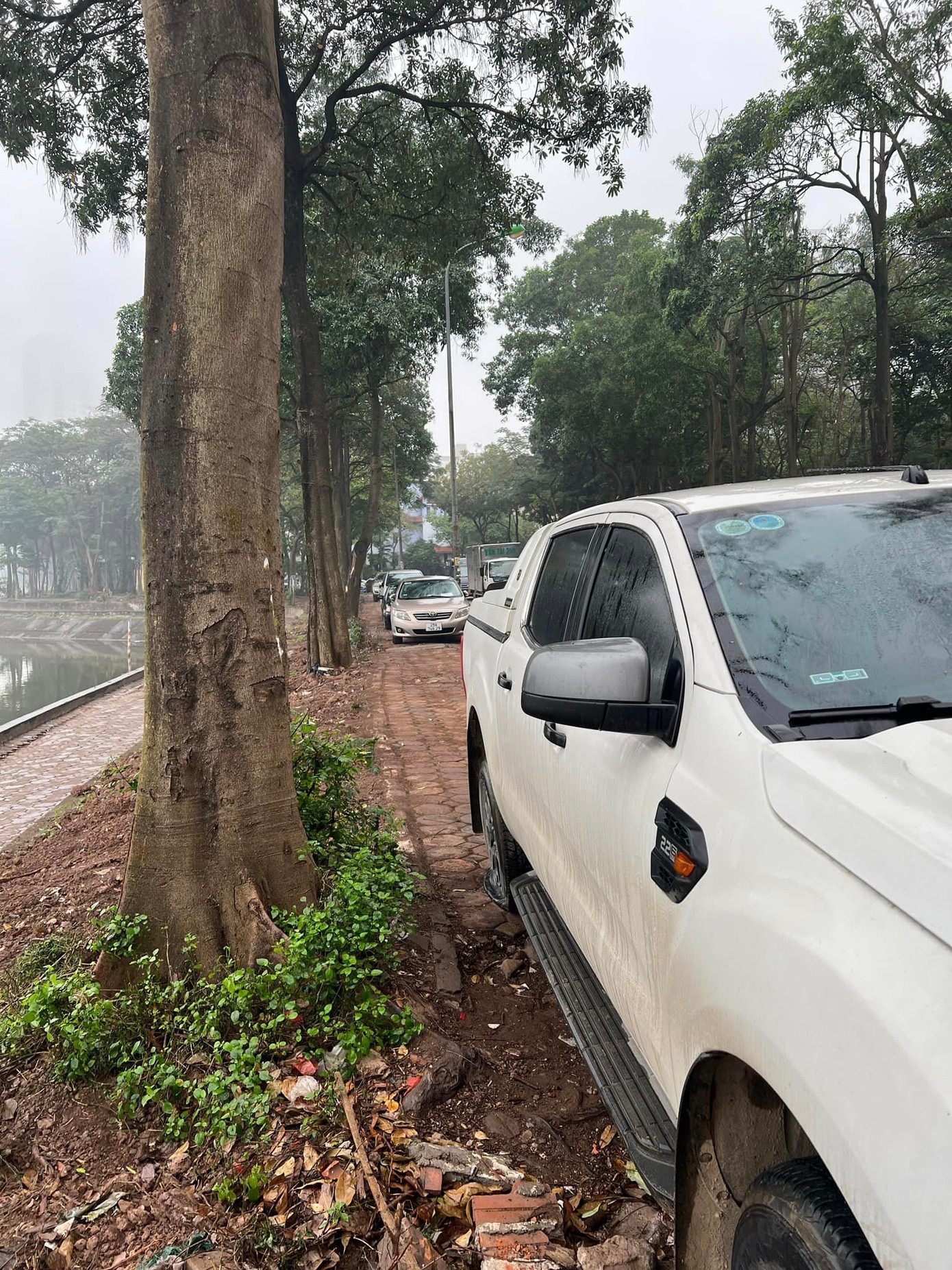 Nhiều xe ô tô để trên vỉa hè bờ hồ Linh Đàm đối diện với tổ hợp chung cư HH Linh Đàm (Hà Nội) bất ngờ bị chọc thủng lốp trong đêm. Ảnh: FB.