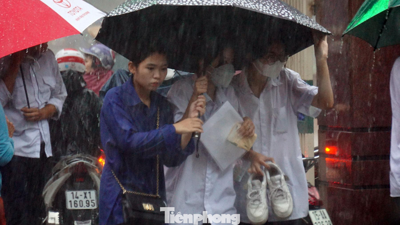 Các bạn sinh viên tình nguyện hỗ trợ che ô cho sĩ tử rời điểm thi trở về nhà để chuẩn bị cho buổi thi tiếp theo.