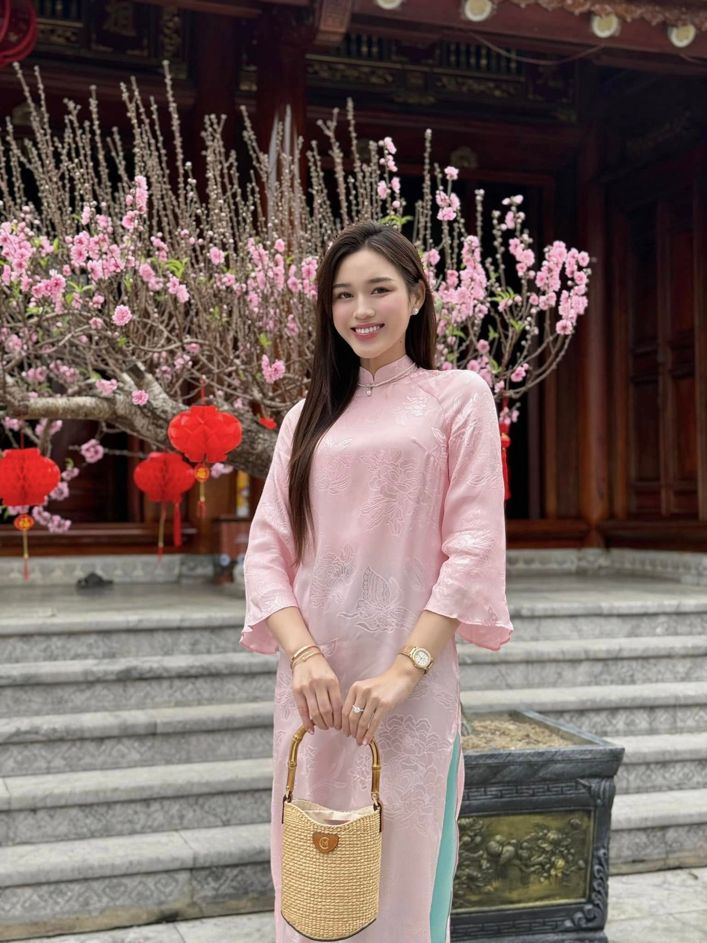 Hoa hậu Việt Nam 2020 chọn áo dài tông màu hồng nhạt nữ tính, để tóc thẳng tự nhiên. Cô khéo léo phối cùng chiếc túi cói, trang điểm nhẹ nhàng.