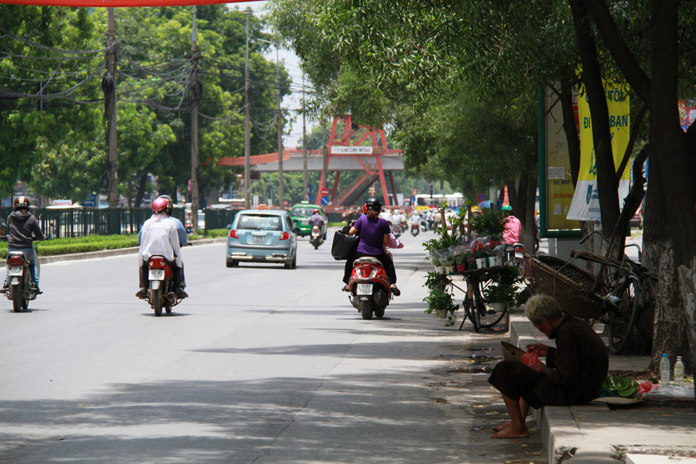 Ông lão bán chuối ngồi nghỉ dưới bóng cây trên đường Nguyễn Trãi (Hà Nội). Ảnh: Trường Phong