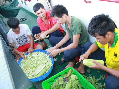 Các thành viên tổ phục vụ đang gọt bí, chuẩn bị nấu ăn trên tàu. Ảnh: Trường Phong