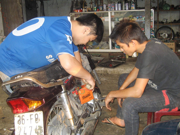 Anh Trần Đình Giang (trái) đang sửa chữa xe máy.Ảnh: K.N - TV