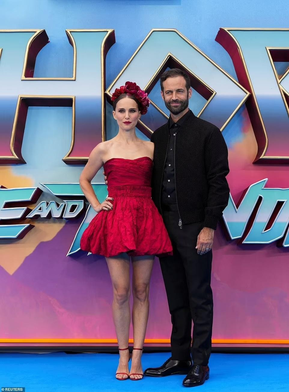 Là nữ chính của &quot;Thor: Love and Thunder&quot;, Natalie Portman nổi bật với chiếc váy ngắn quây màu đỏ và cài tóc đồng bộ. Tháp tùng nàng &quot;Thiên nga đen&quot; là ông xã Benjamin Millepied.