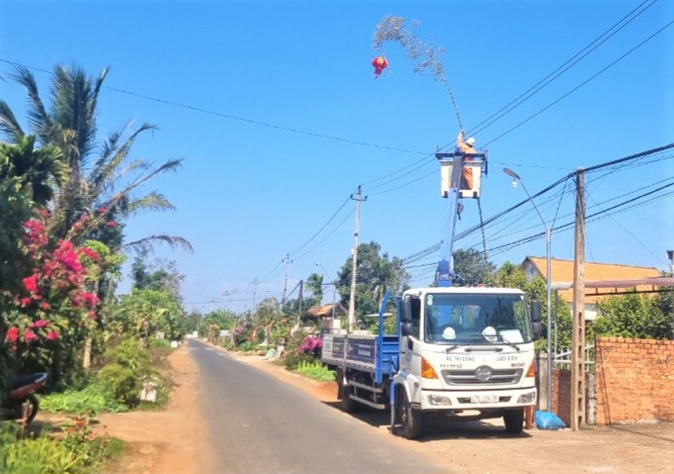 Công nhân Điện lực Cư Kuin hỗ trợ hạ độ cao cây nêu để tránh vi phạm an toàn lưới điện