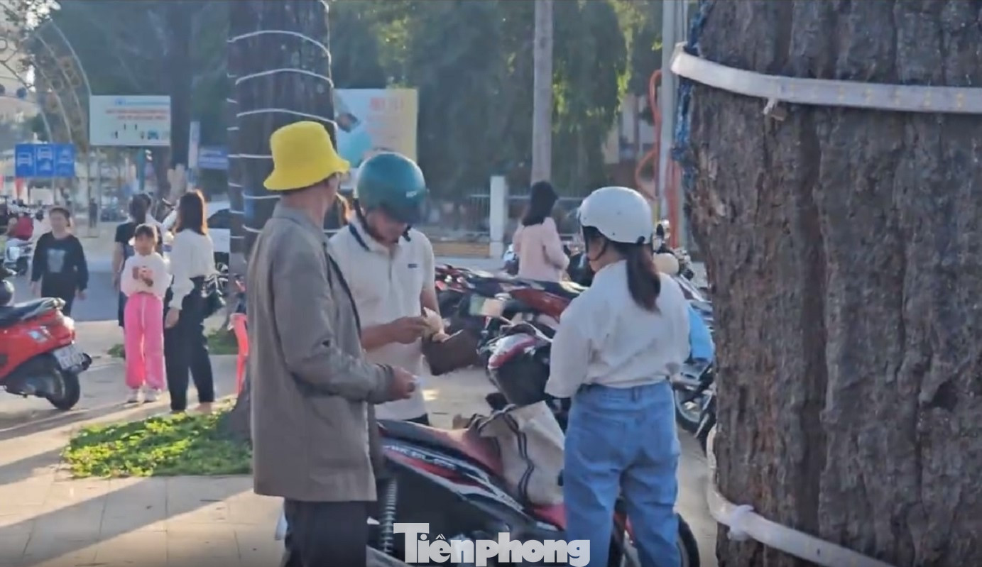 Người đàn ông (đội mũ vàng), thu tiền giữ xe của khách