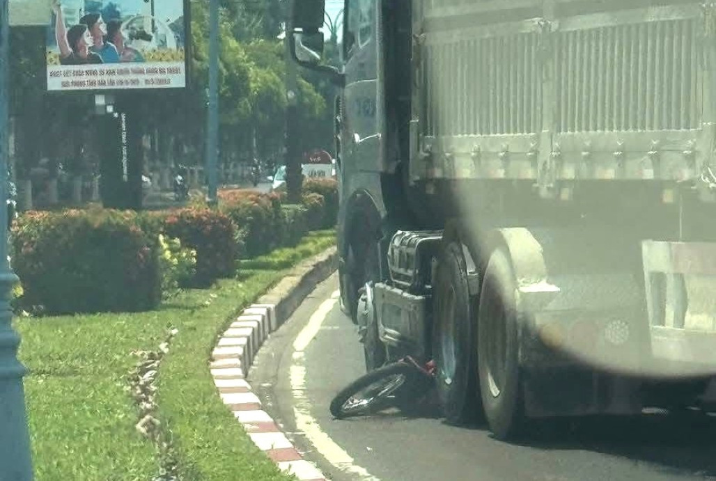 Xe máy bị cuốn vào gầm xe khiến người vợ tử vong.