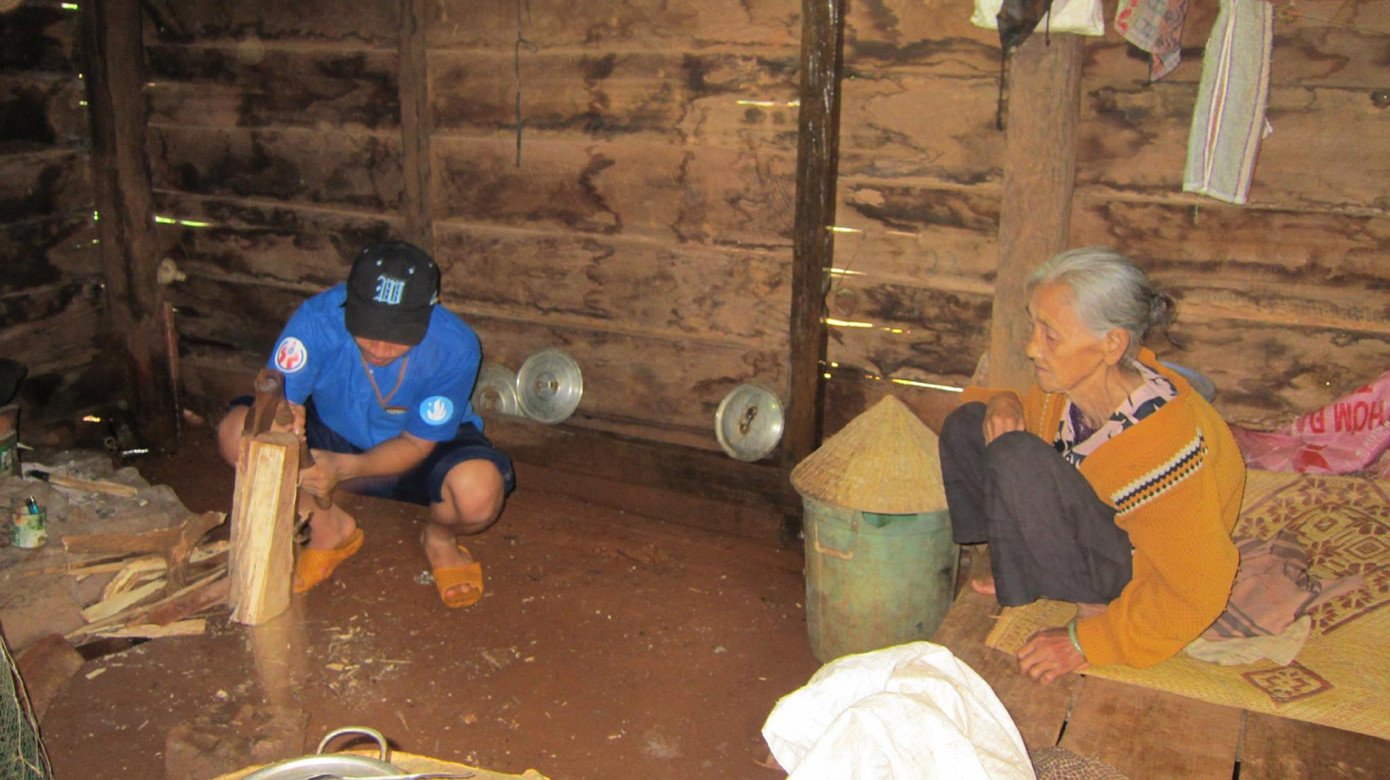 Tình nguyện viên giúp cụ bà chẻ củi