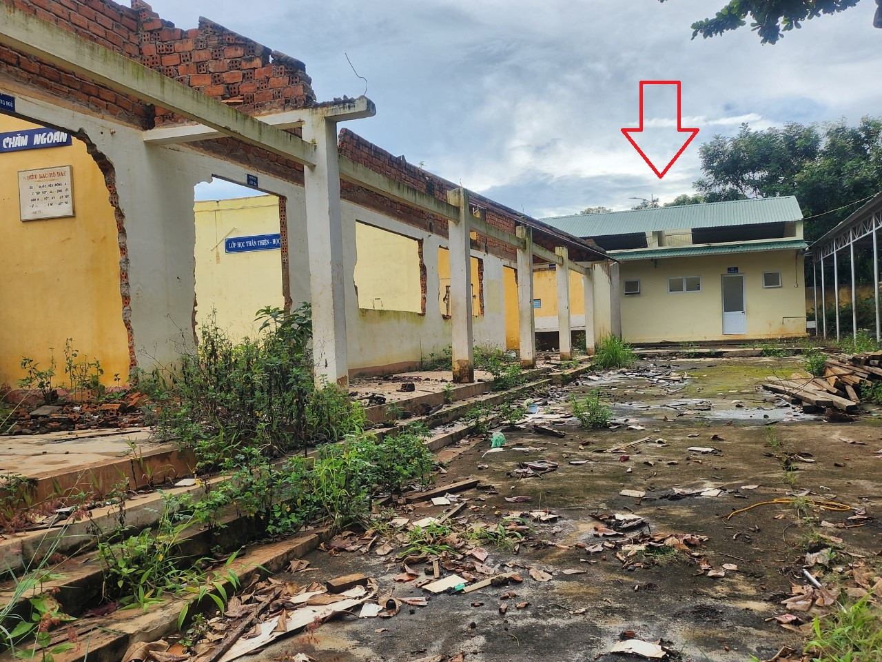 Nhà vệ sinh mới (mũi tên chỉ) nằm trong khu vực đang xây lại phòng học nên phải rào chắn, không sử dụng