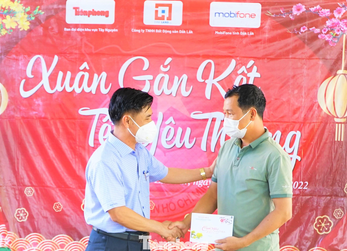 Bí thư Chi bộ buôn Jung (bìa phải) nhận phần quà từ ông Võ Tấn Huy- Chủ tịch UBND huyện Cư Kuin trao tặng đồng bào trong buôn