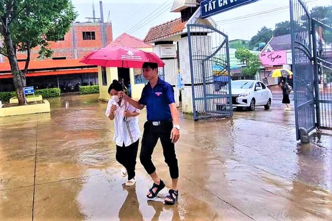 Tình nguyện viên che ô cho thí sinh giữa cơn mưa