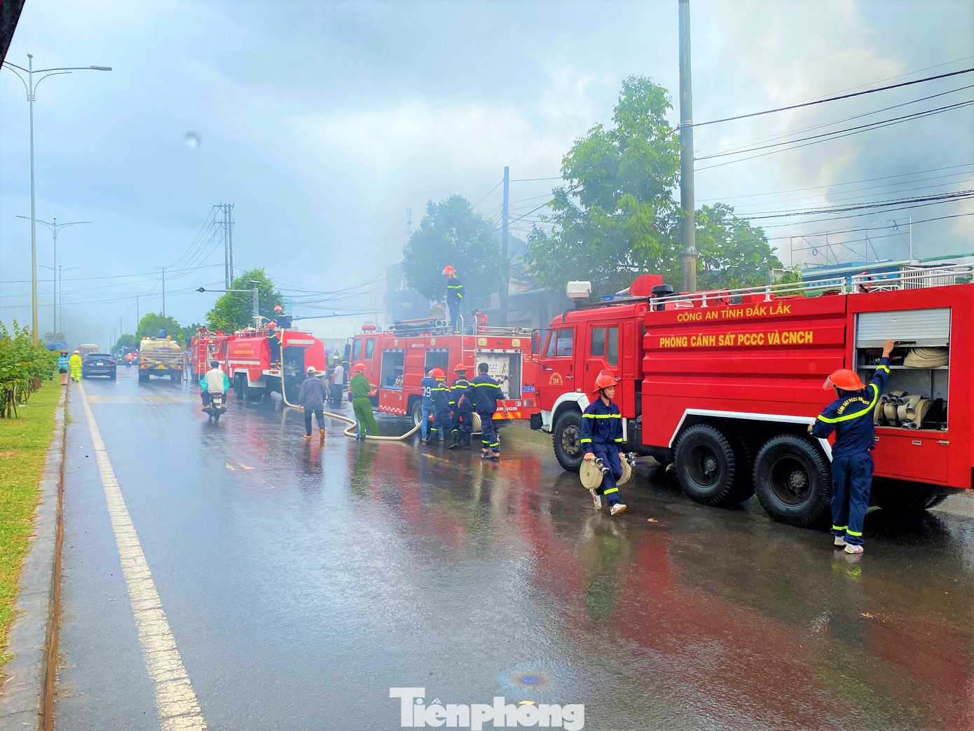 Trời đang mưa to nhưng do đám cháy vẫn bốc khói nghi ngút. Rất đông các cán bộ chiến sĩ dầm mình cứu hộ, cứu nạn, dập tắt đám cháy.