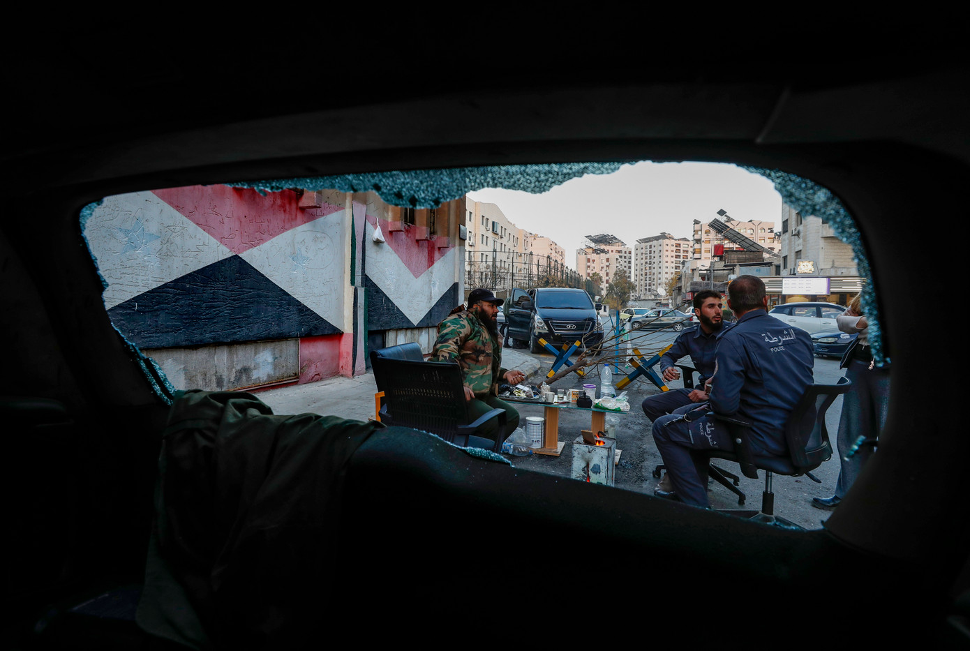 Nhóm tay súng bảo vệ một đồn cảnh sát ở Damascus được nhìn qua cửa sổ kính vỡ ngày 17/12. (Ảnh: AP)