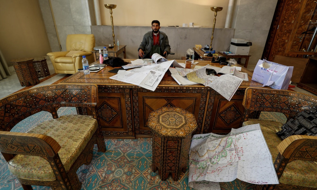 Một tay súng thuộc phe đối lập chụp ảnh trong phòng làm việc của tổng thống. (Ảnh: AP)