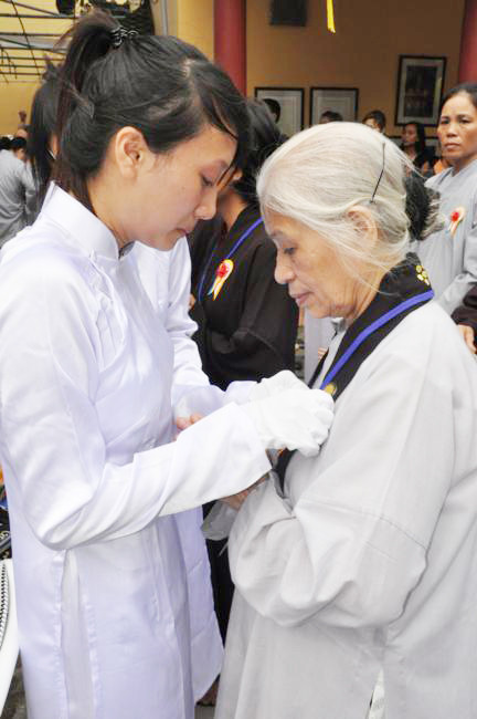 Cài hoa hồng lên áo cho người dự khóa tu Báo hiếu mùa Vu Lan. Ảnh: chuabang.com