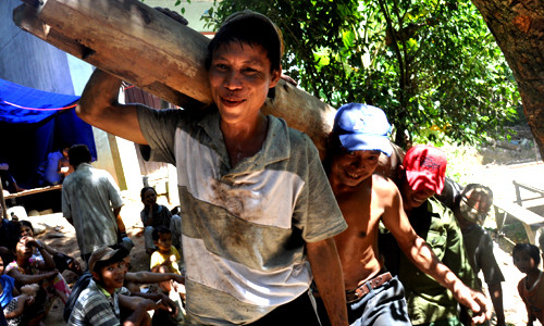 Anh vui vẻ cùng mọi người khiêng những trụ gỗ cột nhà cũ ra ngoài để lấy mặt bằng xây nhà mới