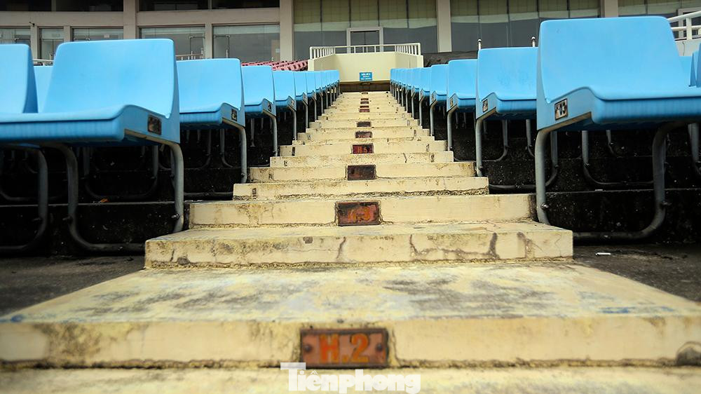 Lối đi xuống khán đài, các biển hiển thị hàng ghế đã hoen rỉ không thể nhận biết.