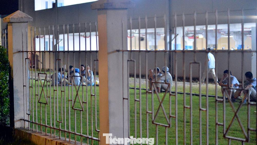 Bên trong khuôn viên của công ty, công nhân túm tụm đợi chờ lấy mẫu xét nghiệm SARS-CoV-2.