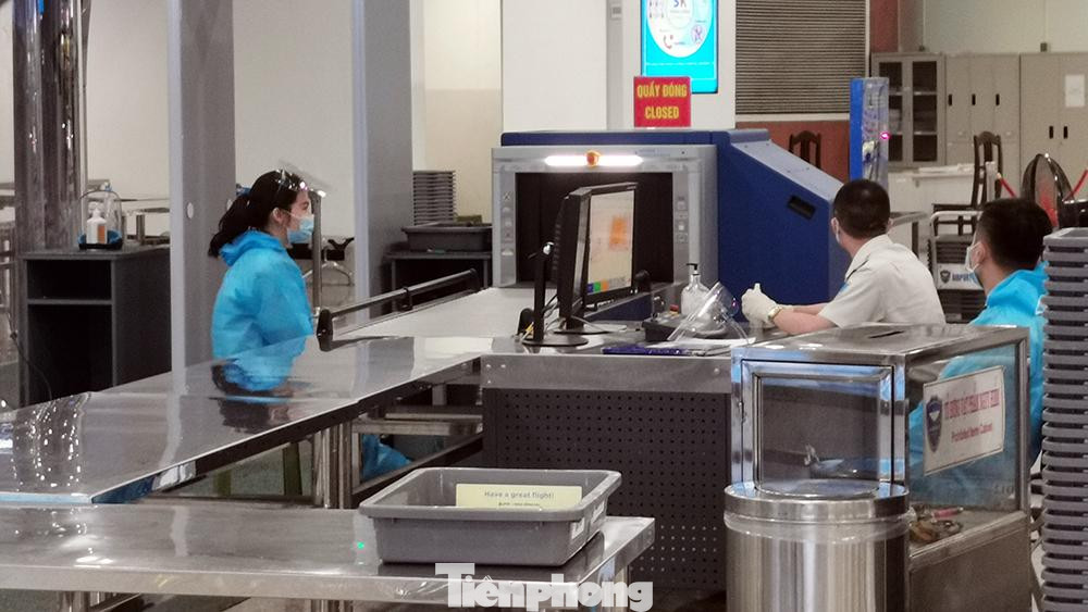 Nhân viên soi an ninh ở sân bay Nội Bài cũng mặc bộ đồ bảo hộ khi làm việc.