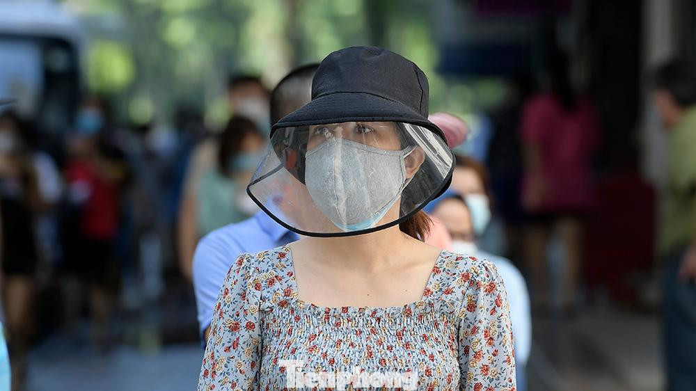 Nhân viên y tế thường xuyên phát loa thông báo mọi người đảm bảo khoảng cách 2m. Càng về trưa, trời càng nắng. Người dân vẫn xếp hàng đội nắng chờ lấy mẫu.