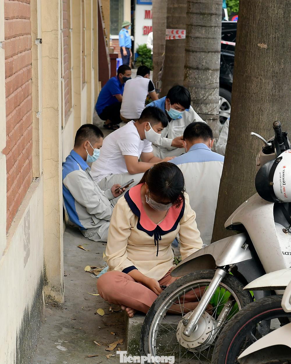 Một số người khác ngồi chờ gần đó để đợi đến lượt vào làm xét nghiệm COVID-19.