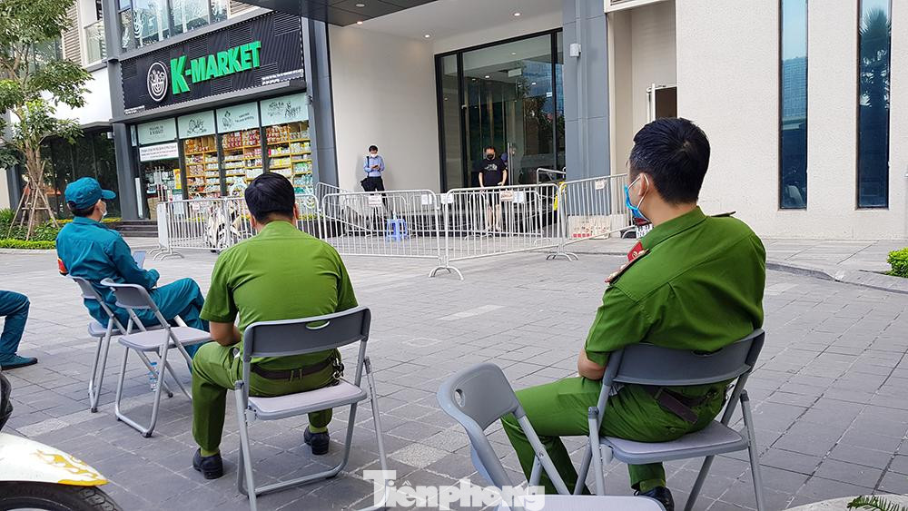 Lực lượng công an và dân quân quận Nam Từ Liêm túc trực trước toà nhà để đảm bảo việc cách ly phòng dịch.