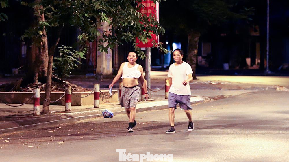 Hai người đàn ông không đeo khẩu trang, thản nhiên "buôn chuyện" khi đi bộ tập thể dục trên đường Tô Hiệu.