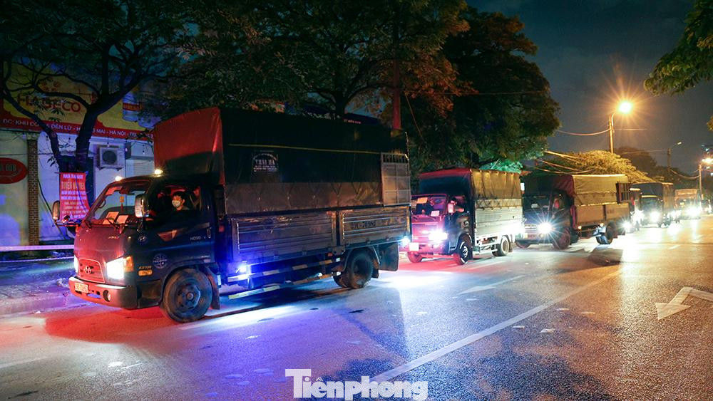 Hàng dài xe tải chở nông sản đứng chờ đến giờ vào chợ trên trục đường Tân Mai (quận Hoàng Mai, Hà Nội).