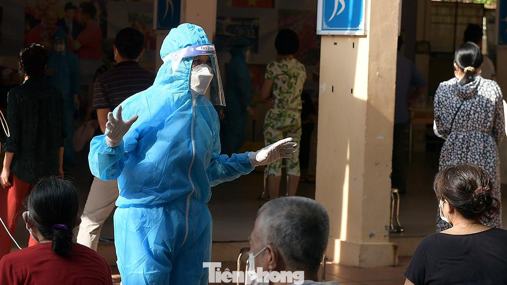 Nhân viên y tế nhắc nhở bà con ngồi giãn cách và tuân thủ các biện pháp phòng dịch khi chờ lấy mẫu xét nghiệm.