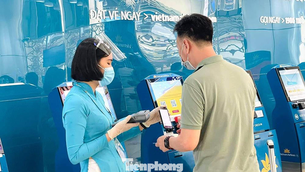 Hành khách vắng vẻ, nhân viên sân bay thoải mái thời gian hướng dẫn hành khách cách khai báo y tế phòng chống dịch tại khu vực check in tự động.