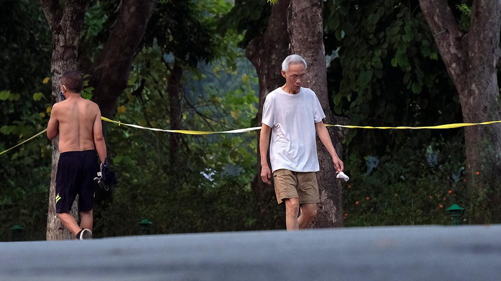 Người đàn ông này cầm khẩu trang trên tay khi đi bộ thể dục trên đường Đinh Tiên Hoàng.