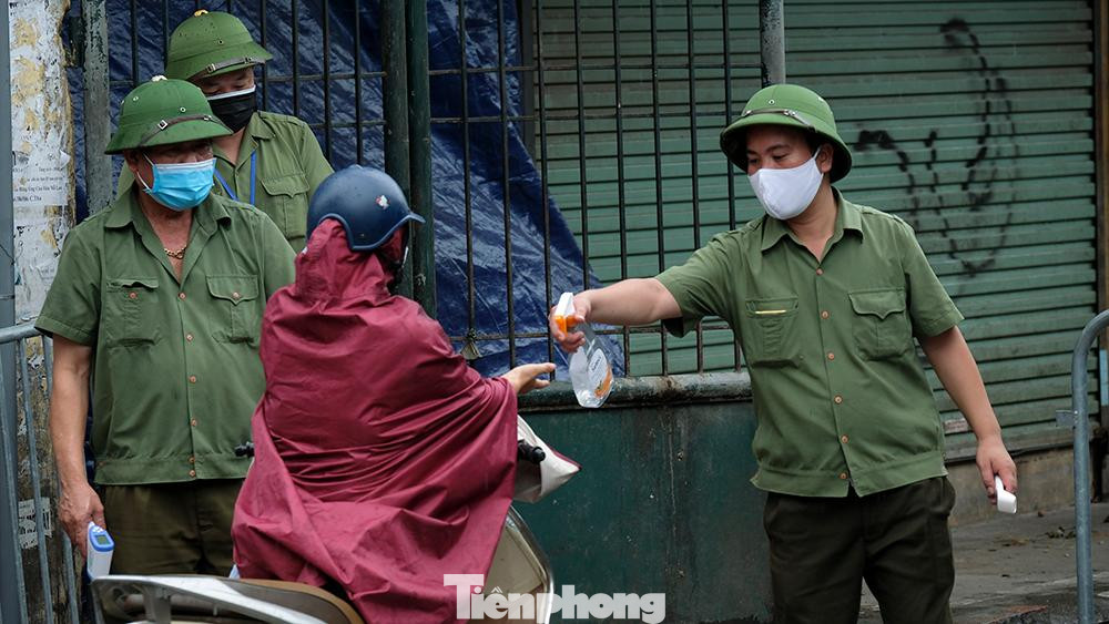 Lực lượng chức năng xịt tay sát khuẩn cho người vào chợ làm việc