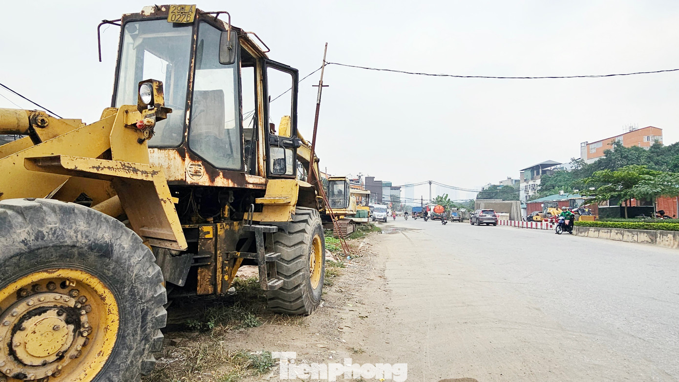 Máy móc thiết bị phục vụ thi công dự án đường Vành đai 2,5 xếp hàng dài bên đường và khu vực văn phòng điều hành.