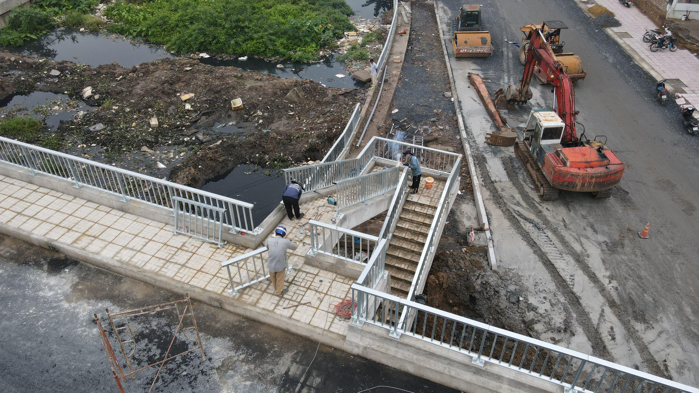 Các công nhân đang thi công lắp lan can ở vị trí lối bộ hành đi lên cầu.