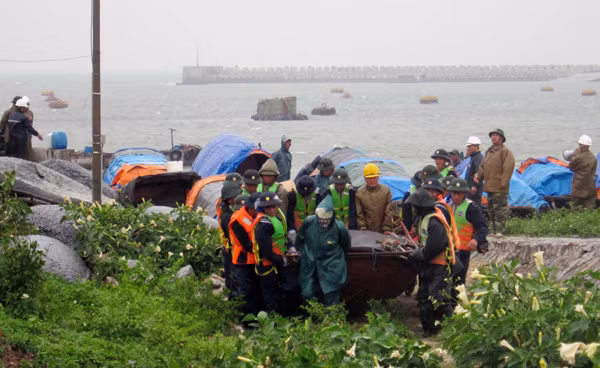 Bộ đội Hải quân và lực lượng phòng chống lụt bão địa phương giúp ngư dân đưa thuyền vào bờ tránh trú bão số 5