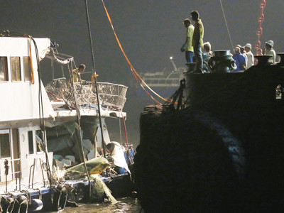 Công nhân nhìn xuống con tàu Lamma IV vừa được trục vớt với những chỗ hư hỏng nghiêm trọng. Ảnh: AP