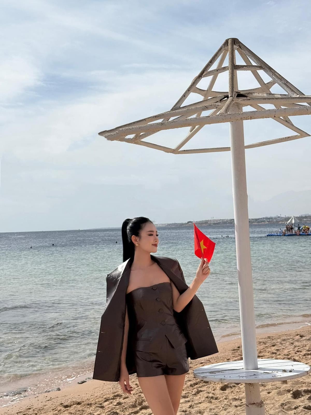 Bùi Khánh Linh cầm lá cờ nhỏ thay cho dải sash để khán giả có thể nhận diện.