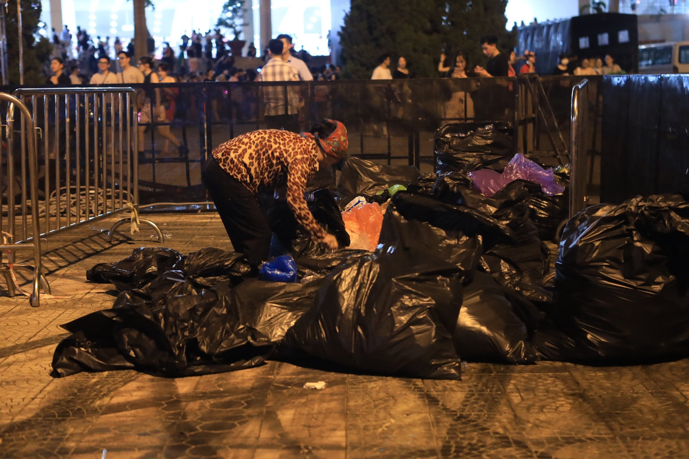 Một người phụ nữ bới tìm trong đống rác những chai nhựa để bán kiếm lời.