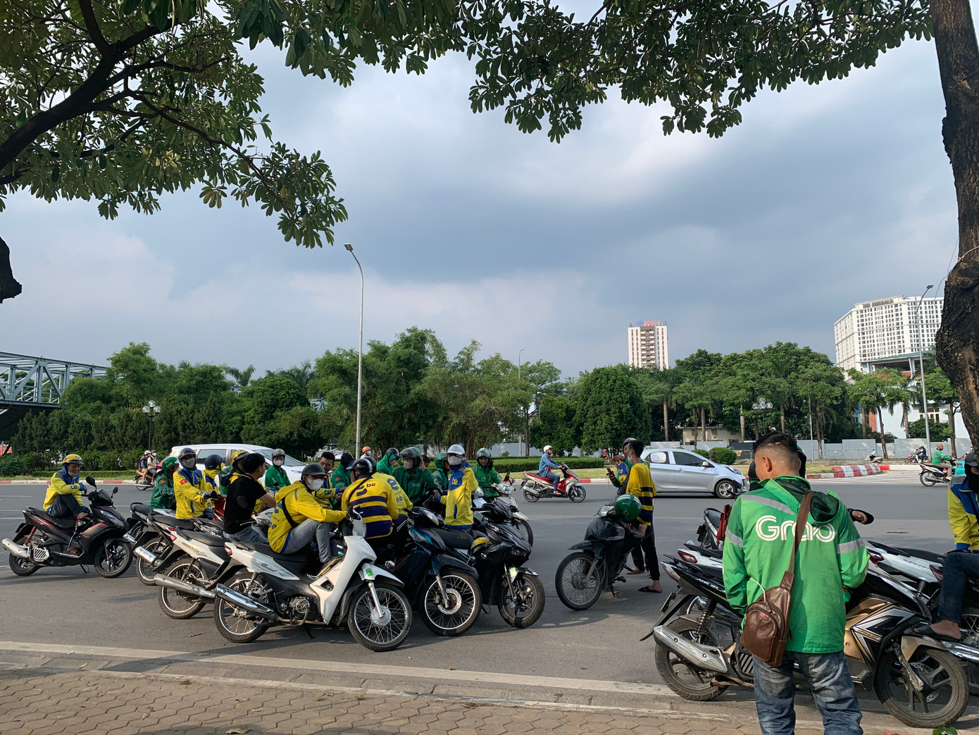 Từng nhóm xe ôm công nghệ ngồi trú nắng đợi khách. Từng nhóm xe ôm công nghệ ngồi trú nắng đợi khách.