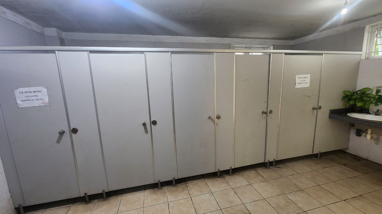 Một nhà vệ sinh nam tại công viên Hòa Bình có 5 bồn cầu thì 2 bồn bị hỏng được dán cảnh báo.
