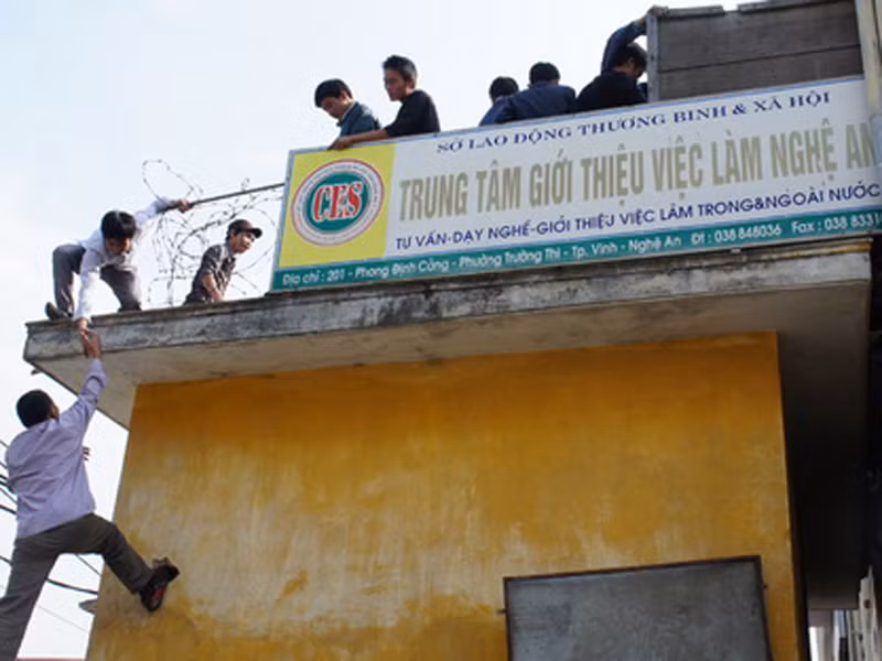 Lao động bất chấp nguy hiểm leo trèo để được đăng ký dự thi tiếng Hàn tại TP Vinh, Nghệ An. Ảnh: A.Khánh