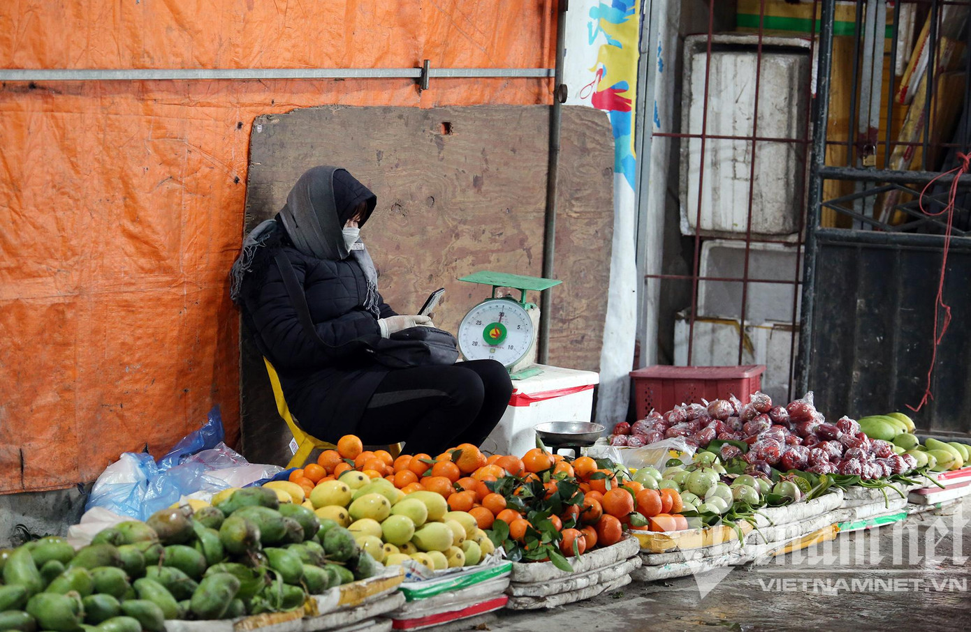 Thời tiết mưa rét, nhiệt độ xuống thấp khiến những người mưu sinh ngoài trời cảm nhận rõ sự khắc nghiệt của cái lạnh thấu xương. Nhưng vì mưu sinh, nhiều hoạt động vẫn tiếp diễn, các sạp hàng bán trái cây dù vắng khách mua nhưng chủ sạp vẫn áo choàng trông hàng. (ảnh chụp tại chợ Phùng Khoang - Hà Nội).