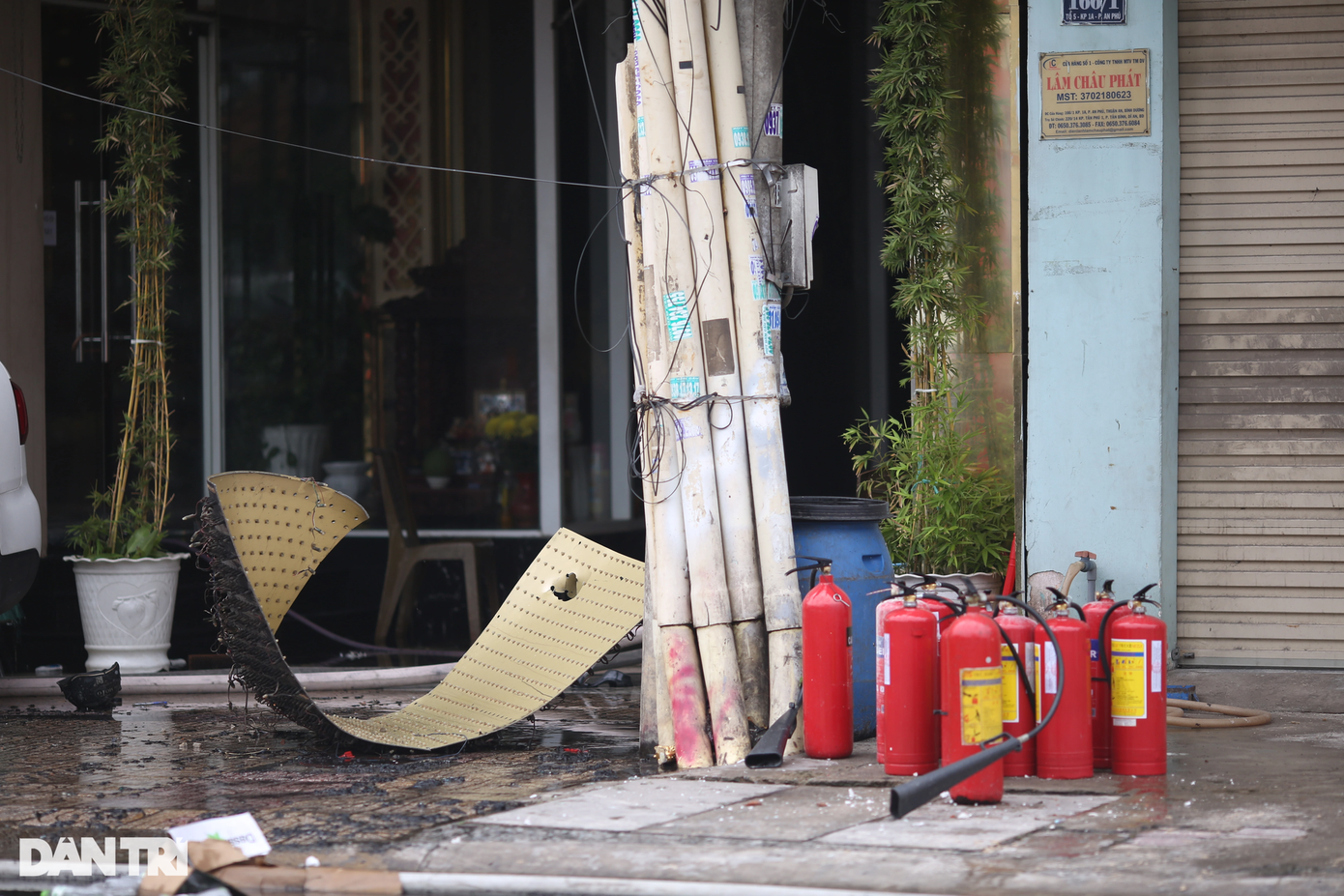 Nhiều bình chữa cháy mini nằm vương vãi, một phần của bảng hiệu rơi xuống trước cửa quán.