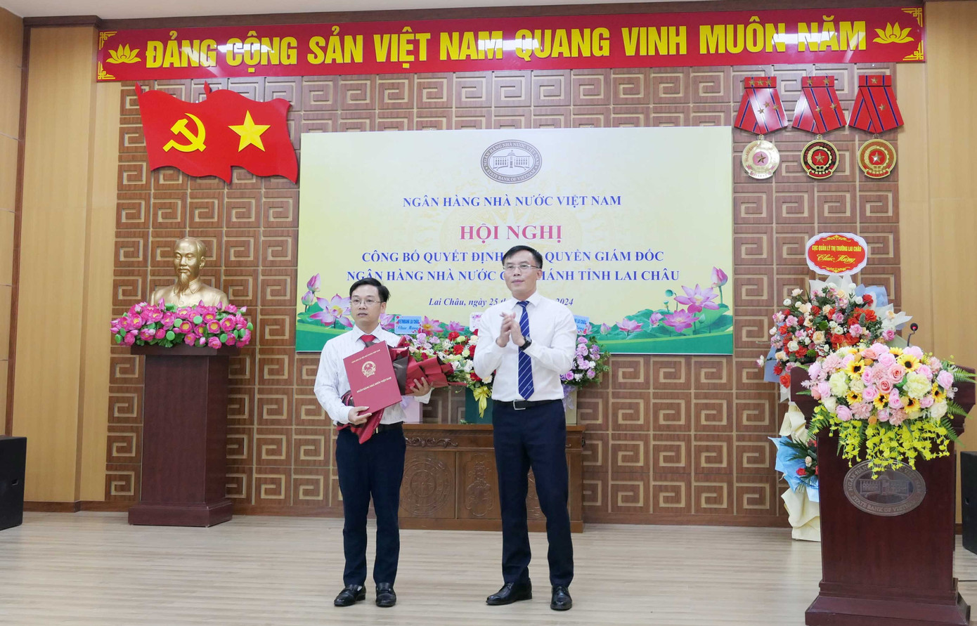 Đồng chí Lê Việt Hùng - Phó Vụ trưởng Vụ Tổ chức cán bộ NHNN Việt Nam trao quyết định và tặng hoa chúc mừng đồng chí Nguyễn Đình Vinh - Quyền Giám đốc NHNN Chi nhánh tỉnh Lai Châu. Ảnh: Báo Lai Châu.